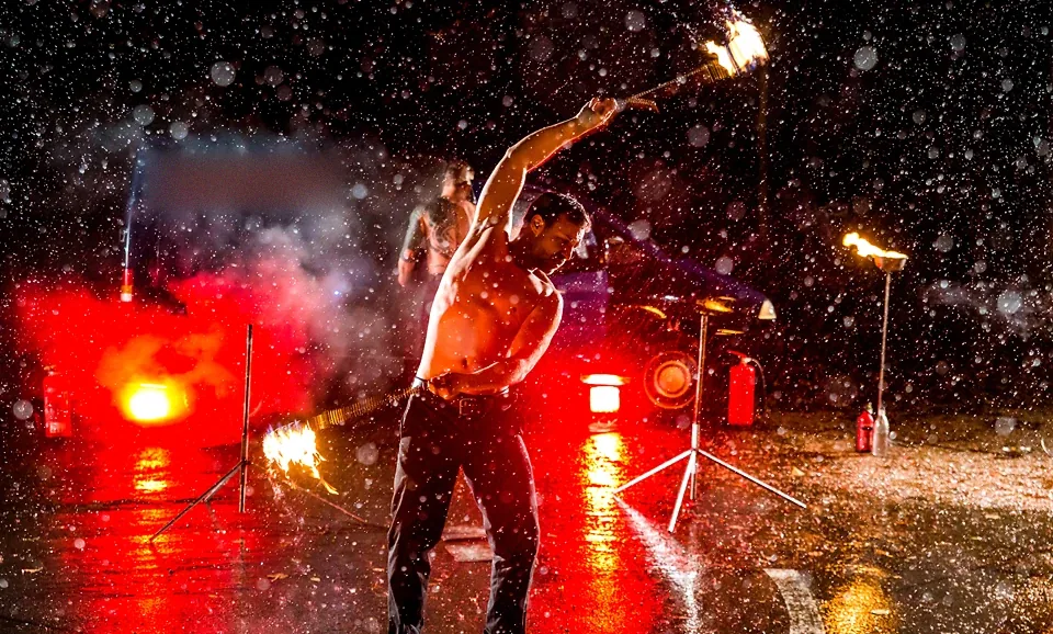 Feuerkünstler schwingt Feuerfackeln während einer Show im strömenden Regen