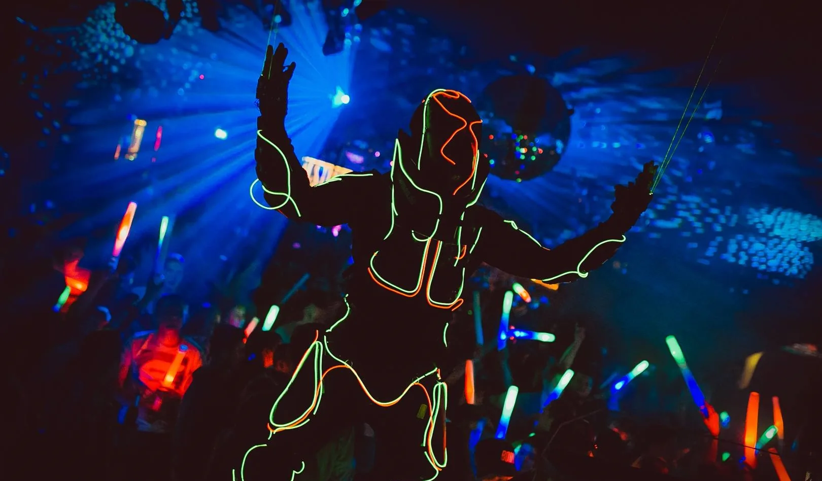LED Performer mit leuchtendem Kostüm vor einer Club-Crowd