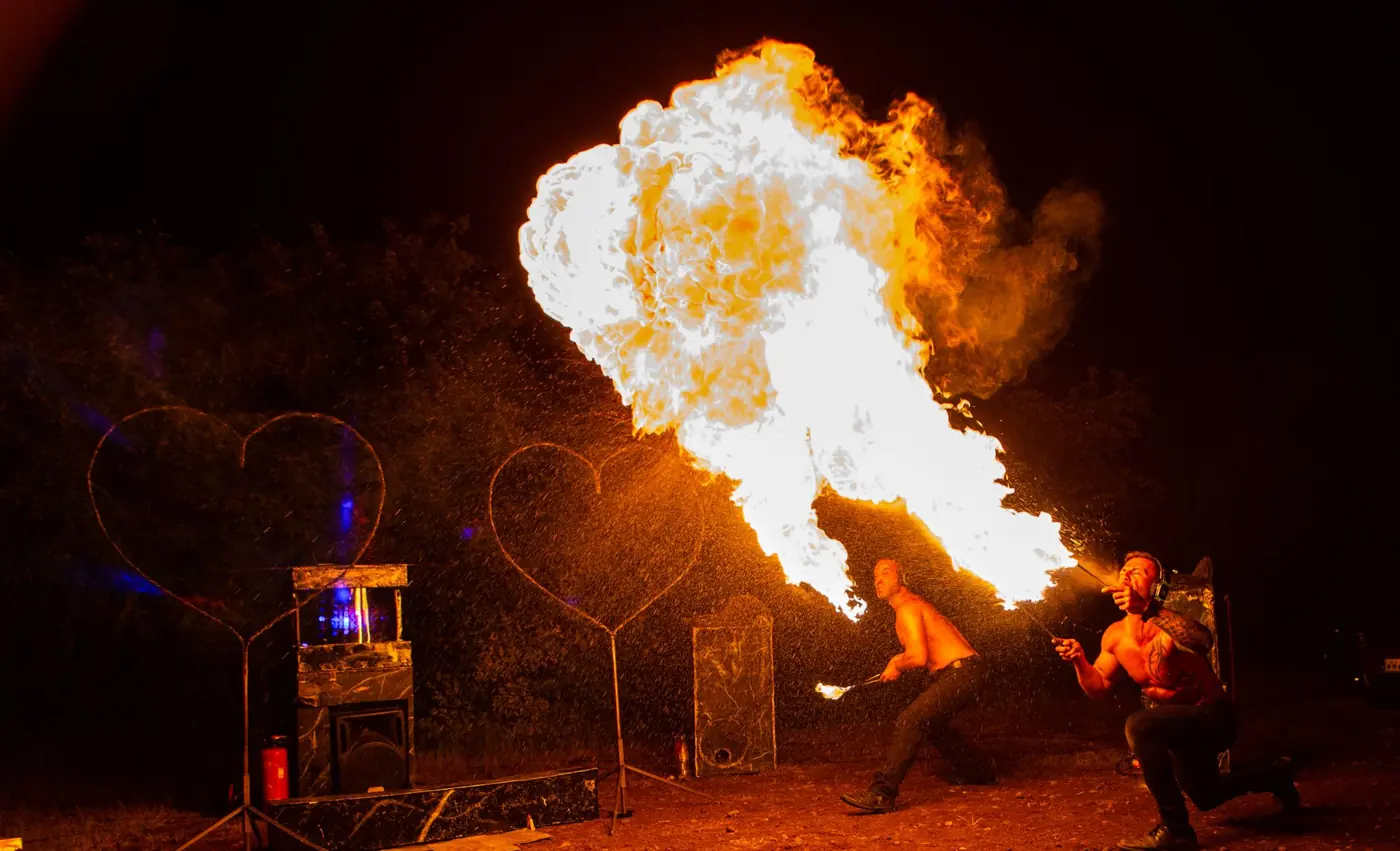 Feuerspucker erzeugt eine riesige Flamme neben zwei Herzen bei einer Hochzeitsfeuershow