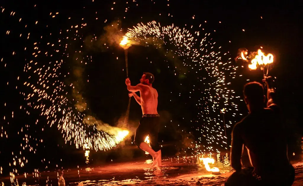 Feuerkünstler mit Funkenregen am Wasser